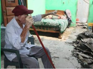 El adulto mayor observa con tristeza el interior de su casa reducido a escombros
